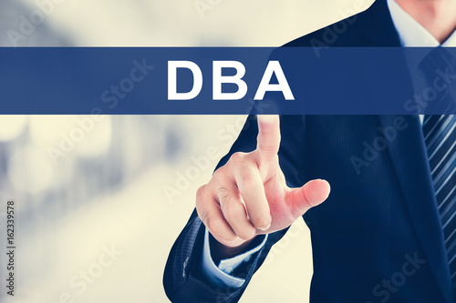 Foto Businessman hand touching DBA (or Doctor of Business Administration) sign on vir
