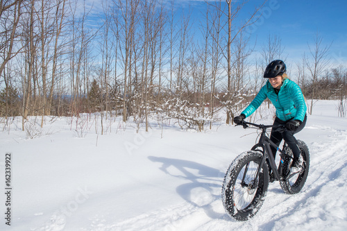 Beautiful woman riding her fat bike in the snow © Colin