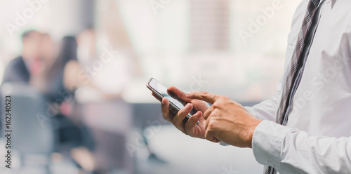 Business man using smart phone in office space background and copy space.