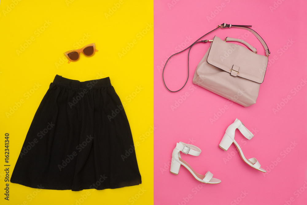 Black skirt, handbag, white shoes and rose-colored glasses. Bright pink-yellow background. Fashionable concept Black skirt, handbag, white shoes and rose-colored glasses. Bright pink-yellow background. Fashionable concept