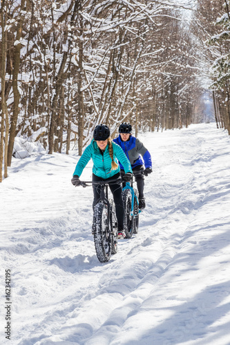 Obraz na płótnie Attractive couple riding fat bikes in the snow w salonie
