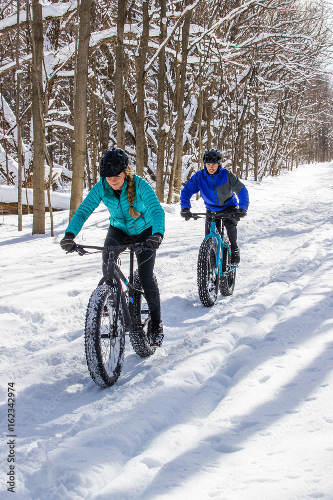 Attractive couple riding fat bikes in the snow