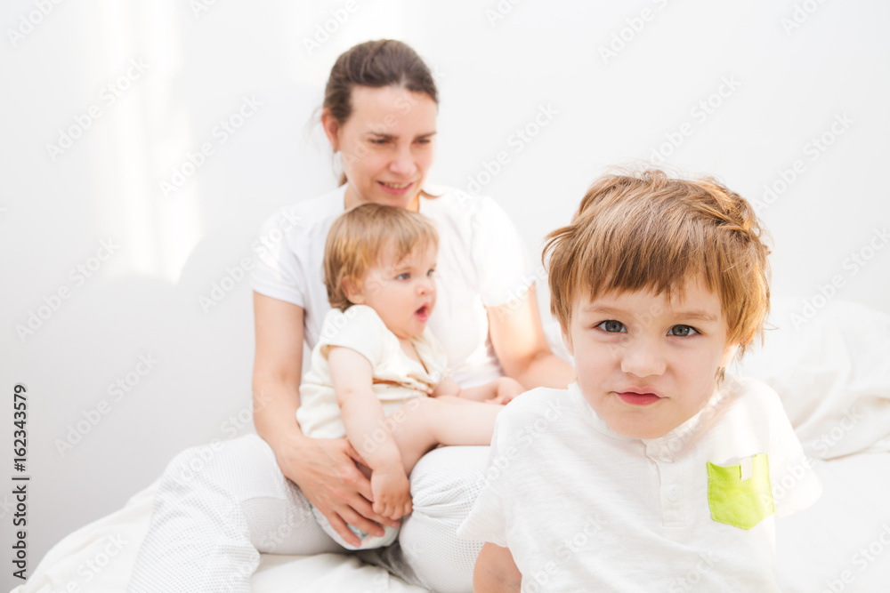 Attractive mother and her children playing in the bedroom. happy family time together at home.. Attractive mother and her children playing in the bedroom. happy family time together at home..