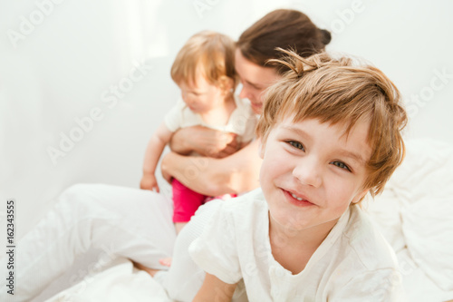 Attractive mother and her children playing in the bedroom. happy family time together at home..