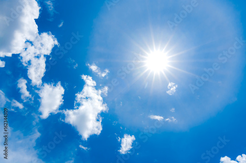 The sun with blue sky and fluffy white clouds in summer.