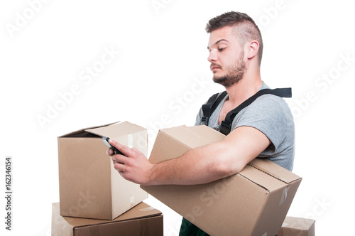 Mover man holding cardboard box and texting smartphone