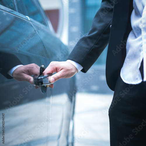 Hand of businessman opening door of car