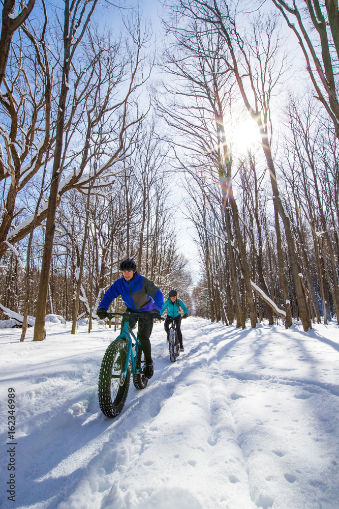 Attractive couple riding fat bikes in the snow