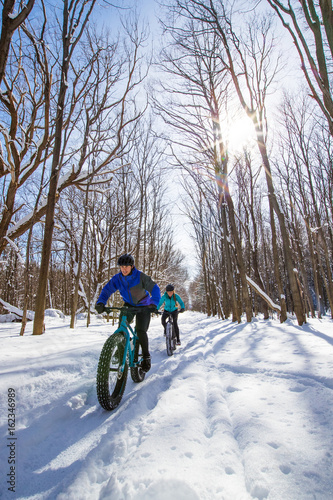 Obraz na płótnie Attractive couple riding fat bikes in the snow w salonie