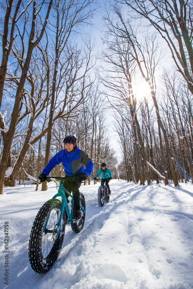 Attractive couple riding fat bikes in the snow