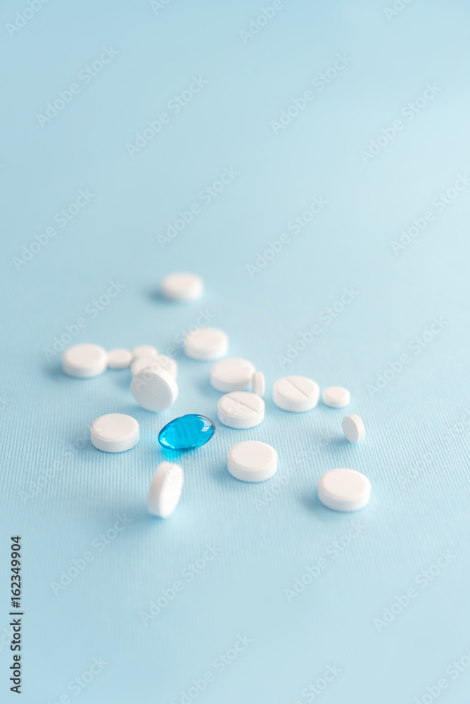 Close up of white tablets with one blue capsule
