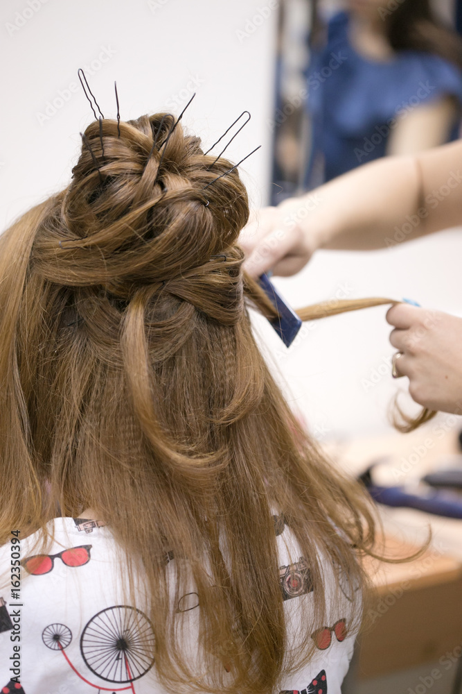 Fototapeta premium a hairdresser does a hairstyle for a girl in a hairdresser's 