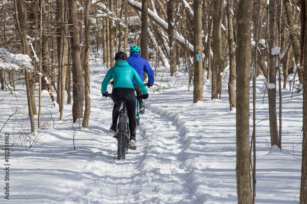 Attractive couple riding fat bikes in the snow