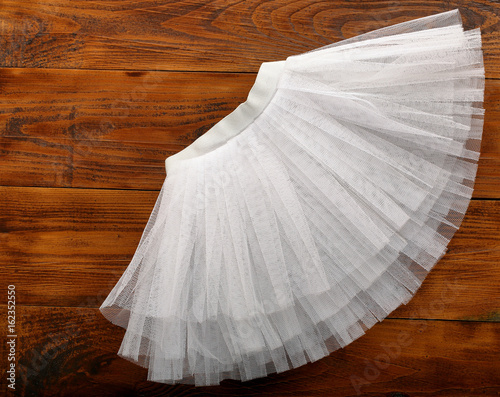 White tutu skirt on wooden background with empty space for text photo