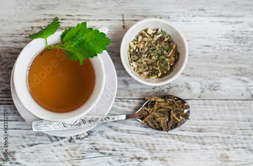 Green tea with mint, drink in a cup close up. On a wooden, light background.