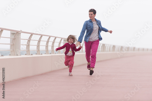 mother and cute little girl on the promenade by the sea