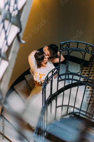 The newlyweds are kissing on the stairs. The above view. photo