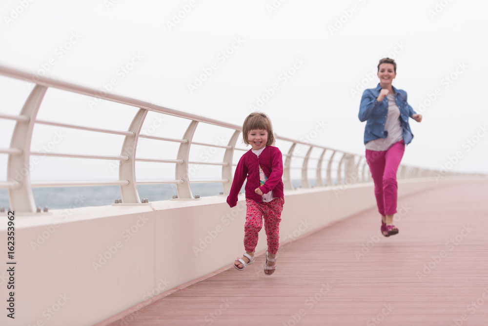 Obraz premium mother and cute little girl on the promenade by the sea