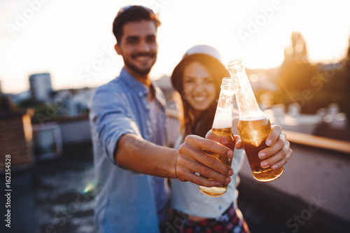 Tableau sur toile Young happy couple toasting with beer outdoors