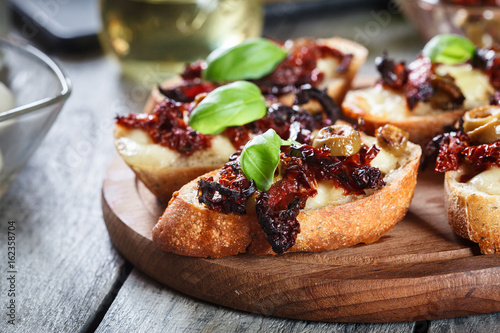 Appetizer bruschetta with sun-dried tomatoes, olives and mozarella.