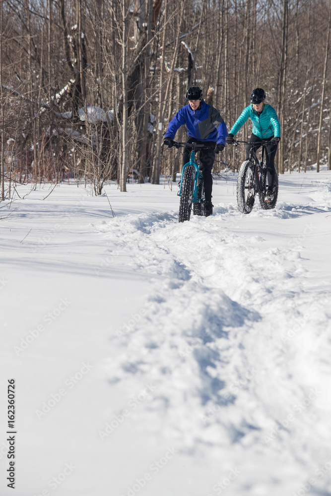 Attractive couple riding fat bikes in the snow