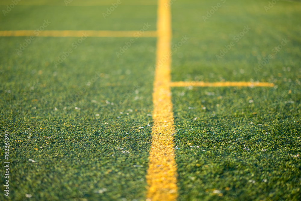 Detail of an artificial turf with yellow lines. Photo with low depth of field.