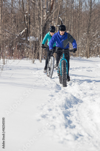 Attractive couple riding fat bikes in the snow