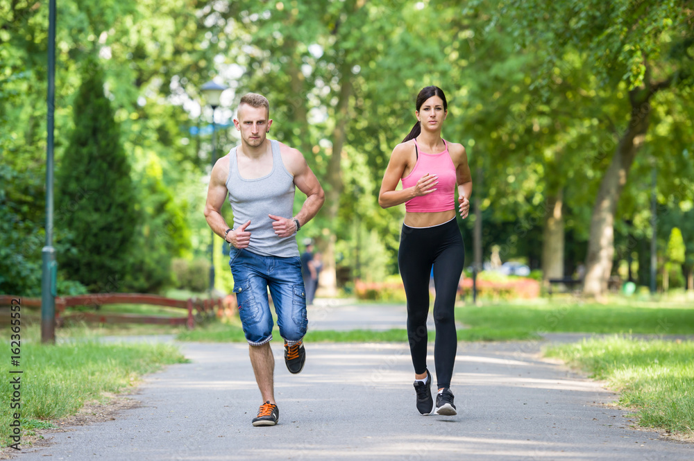 sport woman and man running together in a park in summer