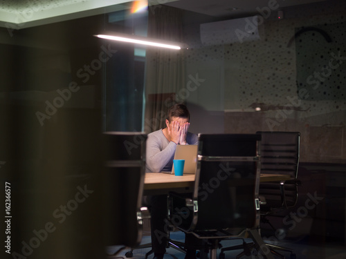 man working on laptop in dark office