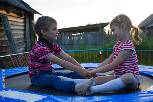 Two funny kids jumping on a outdoor trampoline. photo