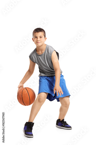 Full length portrait of a kid playing with a basketball