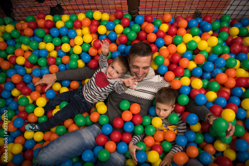 Young dad with kids in a children's playroom photo