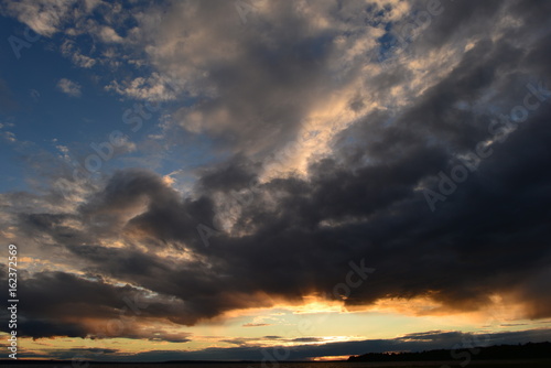 Glowing abyss in the cloudy sky at sunset over the lake