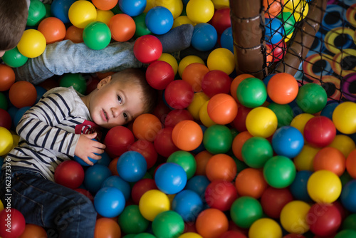 boy having fun in hundreds of colorful plastic balls photo