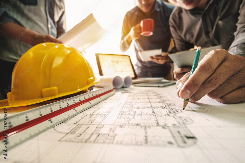 Three colleagues discussing data working and tablet, laptop with on on architectural project at construction site at desk in office
Three colleagues discussing data working and tablet, laptop with on on architectural project at construction site at desk in office