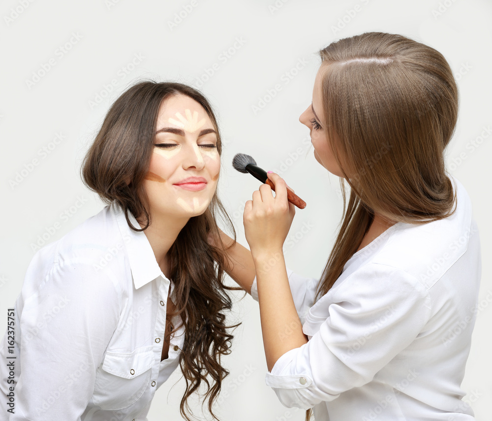 Applying Make-up. Woman with a brush for make-up.Female friends putting makeup Applying Make-up. Woman with a brush for make-up.Female friends putting makeup
