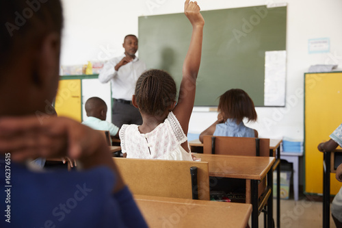 Kids with hands up in elementary school class, low angle