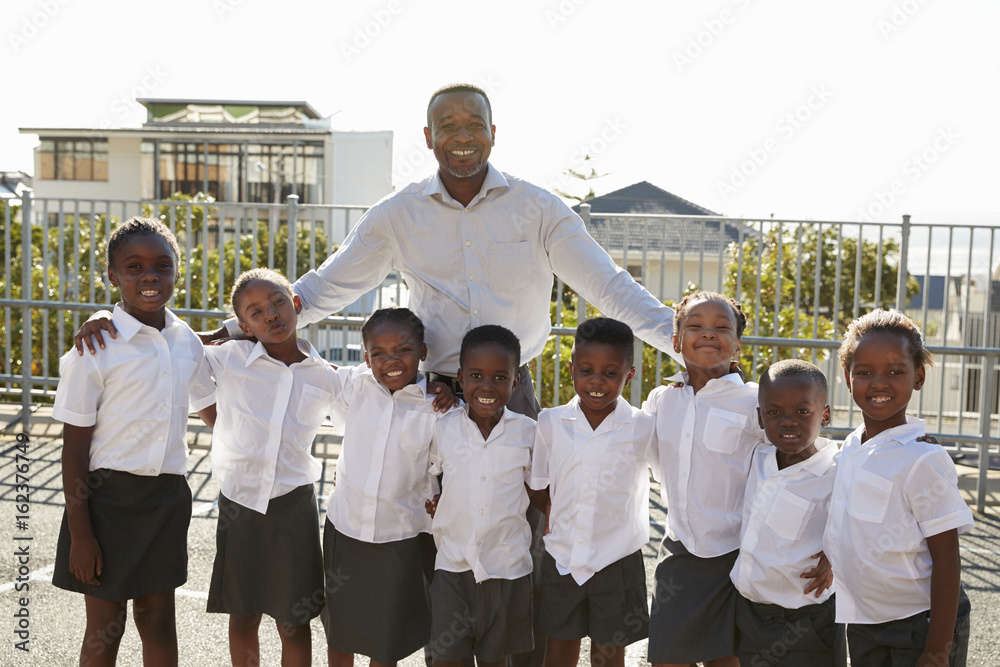 Fototapeta premium Teacher and elementary school kids in playground, portrait