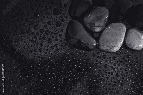 water rain drop with stones on shiny luxury black for spa , relaxation and meditation background concept