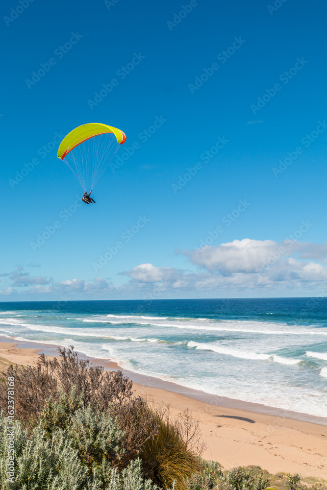 Paraglider above the ocean going towards the water in Australia Paraglider above the ocean going towards the water in Australia