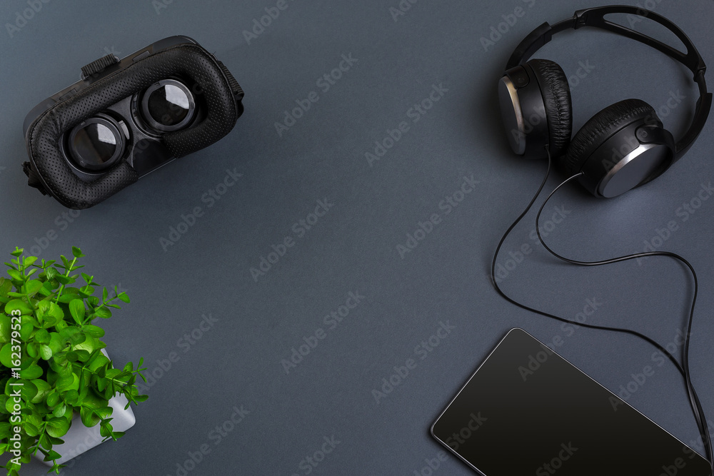 Virtual reality glasses and tablet with headphones on a gray background. Top view Virtual reality glasses and tablet with headphones on a gray background. Top view