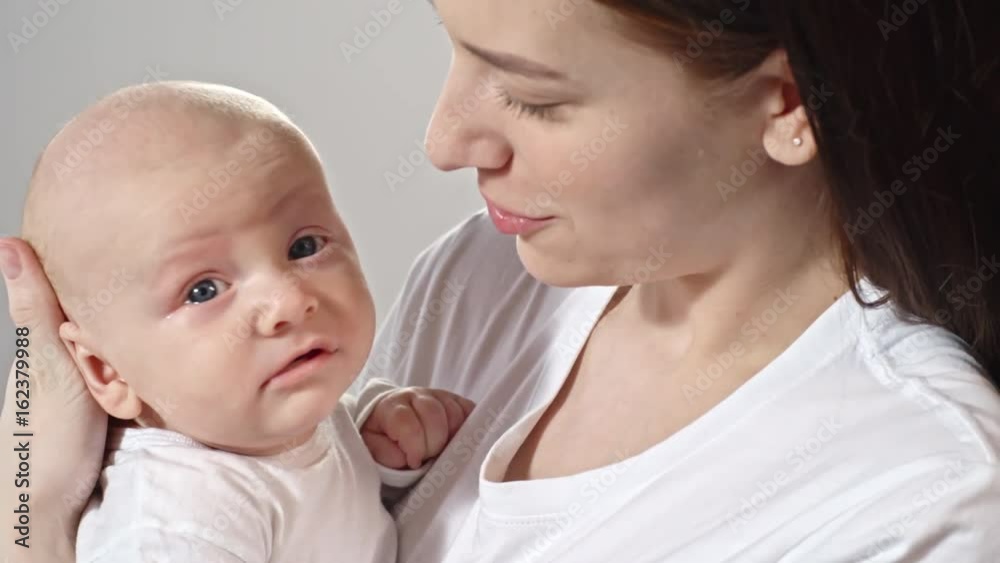 Tilt up of young mother holding yawning baby boy on arms and telling something Tilt up of young mother holding yawning baby boy on arms and telling something