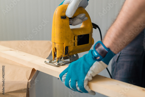 Carpenter handyman using electric handy saw photo