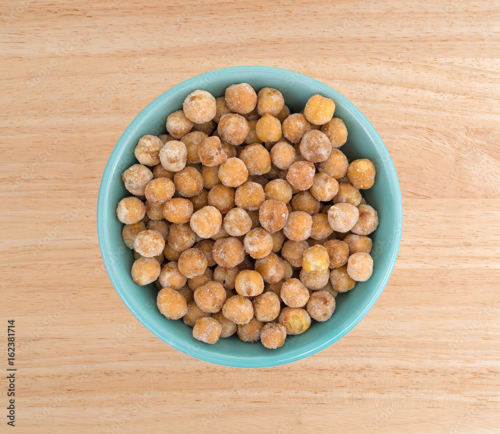 A serving of honey roasted chickpeas in a bowl atop a wood table. A serving of honey roasted chickpeas in a bowl atop a wood table.