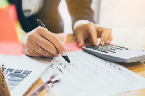 Close up Business man using calculator and laptop computer for calculating with finance paper, tax, accounting, Accountant concept.