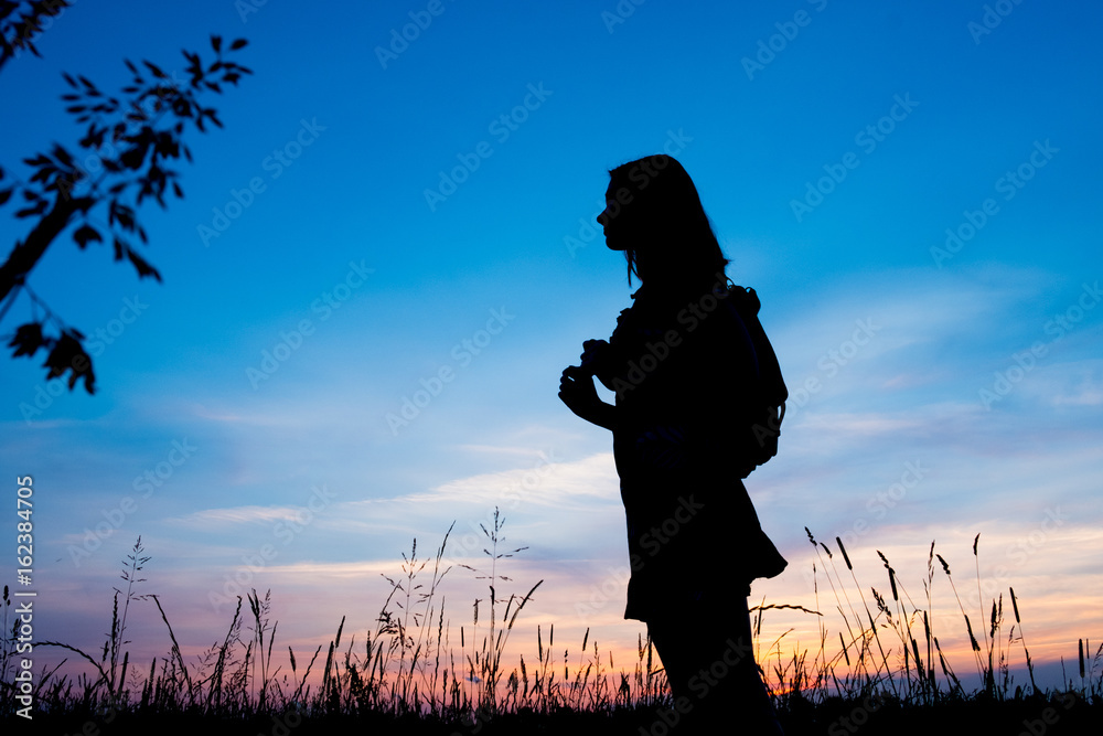 Girl enjoys the sunrise with a view of the beautiful sky. Portrait in profel. Traveler's style