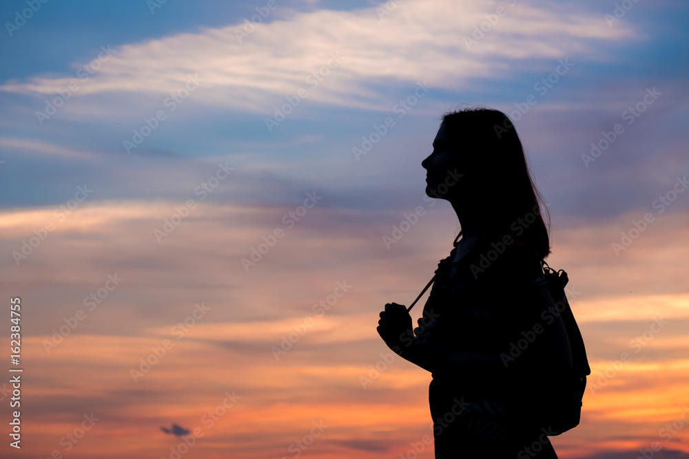 Girl enjoys the sunrise with a view of the beautiful sky. Portrait in profel.