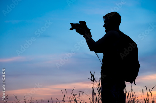 Silhouette of a young who like to travel and photographer, taking pictures of the beautiful moments during the sunset ,sunrise. photo