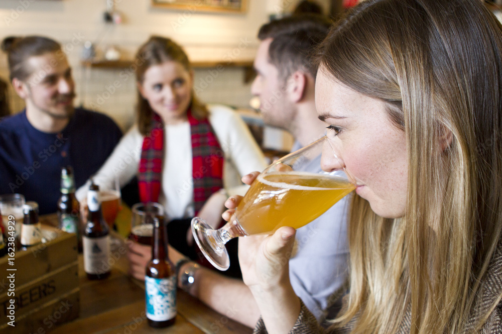 Young woman tasting beer in pub, Dorset, Bournemouth, England Young woman tasting beer in pub, Dorset, Bournemouth, England