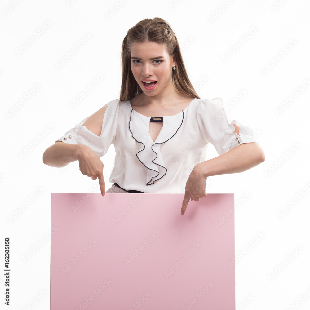 Young glad woman portrait of a confident businesswoman showing presentation, pointing paper placard pink background. Ideal for banners, registration forms, presentation, landings, presenting concept.. Young glad woman portrait of a confident businesswoman showing presentation, pointing paper placard pink background. Ideal for banners, registration forms, presentation, landings, presenting concept..